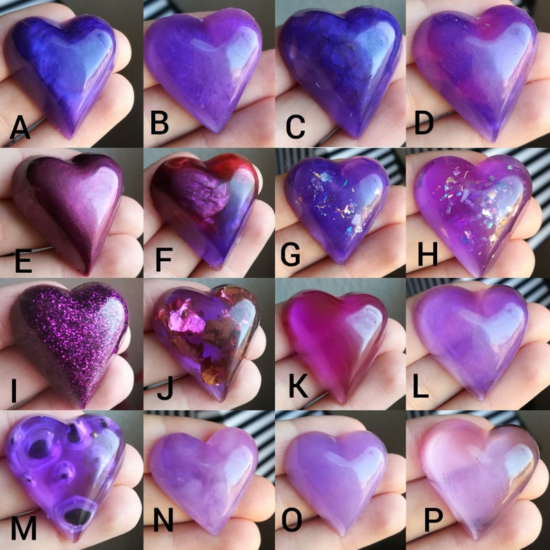 May include: Assortment of 16 heart-shaped resin crafts in various shades of purple, pink, and glitter. The hearts are arranged in four rows of four, with each heart having a letter label from A to P.