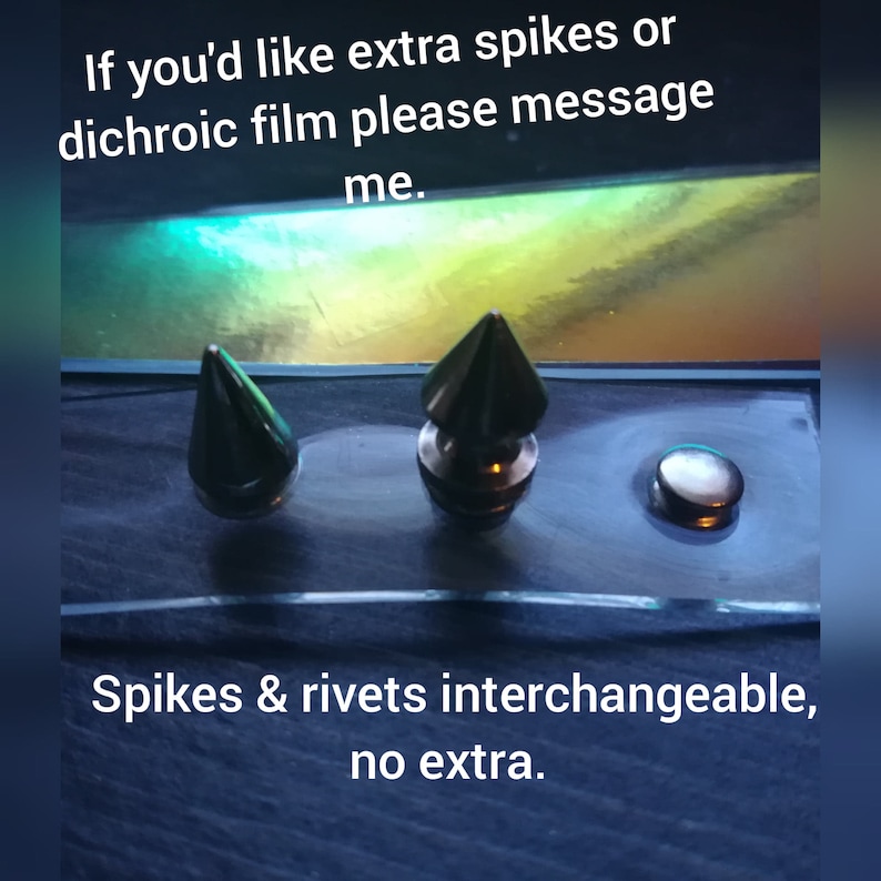 Puede incluir: Tres adornos met&aacute;licos sobre una superficie transparente. Dos son p&uacute;as plateadas y uno es un remache plateado. El texto "If you'd like extra spikes or dichroic film please message me. Spikes & rivets interchangeable, no extra." es visible.