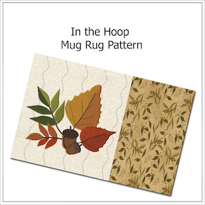 Puede incluir: Un patrón de alfombrilla rectangular con el texto "In the Hoop Mug Rug Pattern". La alfombrilla presenta un diseño bordado de hojas de otoño en tonos naranja, marrón y verde, junto con dos bellotas. El lado derecho tiene un patrón de hojas.