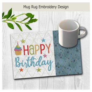 May include: A rectangular mug rug featuring an embroidered birthday design with a cupcake, colorful stars, and the text Happy Birthday. The left side has a white diamond pattern, while the right side is a solid blue fabric with floral outlines.