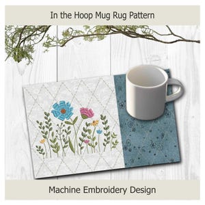 May include: A rectangular mug rug featuring a machine embroidery design of blue, pink, and yellow flowers on a white diamond-quilted background, with a solid blue side panel. A white ceramic mug sits on the right side. Text reads In the Hoop Mug Rug Pattern.