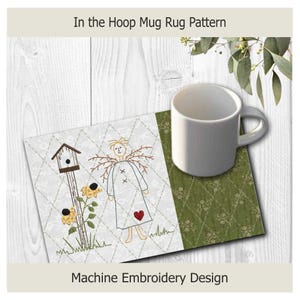 K&ouml;nnte beinhalten: Eine wei&szlig;e Keramiktasse steht auf einem gesteppten Untersetzer. Der Untersetzer zeigt ein gesticktes Design einer Vogelscheuche, Sonnenblumen und eines Vogelhauses. Der Text "In the Hoop Mug Rug Pattern" und "Machine Embroidery Design" sind sichtbar.
