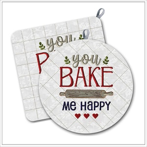 May include: A square and a round white quilted fabric potholder set featuring a grid pattern. The text "you BAKE me happy" is embroidered in gray, red, and dark blue, accompanied by a brown rolling pin graphic and three small red hearts.