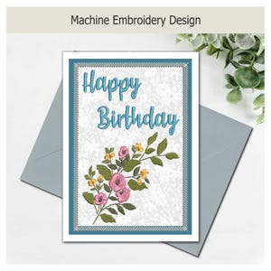 May include: A rectangular machine embroidery design featuring the text Happy Birthday in blue thread. Below the text is a floral arrangement with pink and yellow flowers and green leaves. The design is enclosed in a blue and silver border.