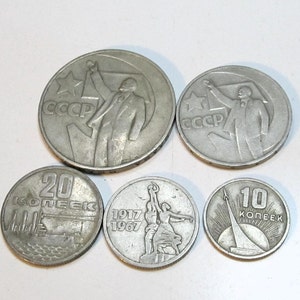 Può includere: Cinque monete in metallo color argento dell'Unione Sovietica. Due monete presentano una figura con un braccio alzato e il testo CCCP. Una moneta mostra il numero 20 e il testo KOPEEK. Una moneta mostra 1917 1967. Una moneta mostra 10 KOPEEK e un razzo.