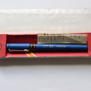 May include: A blue pen with a silver clip and a red and orange box. The box has the text "ручка  тру" and "СССР" on it. The pen has the text "ГР 01" and "ХАРЬКОВ" on it.