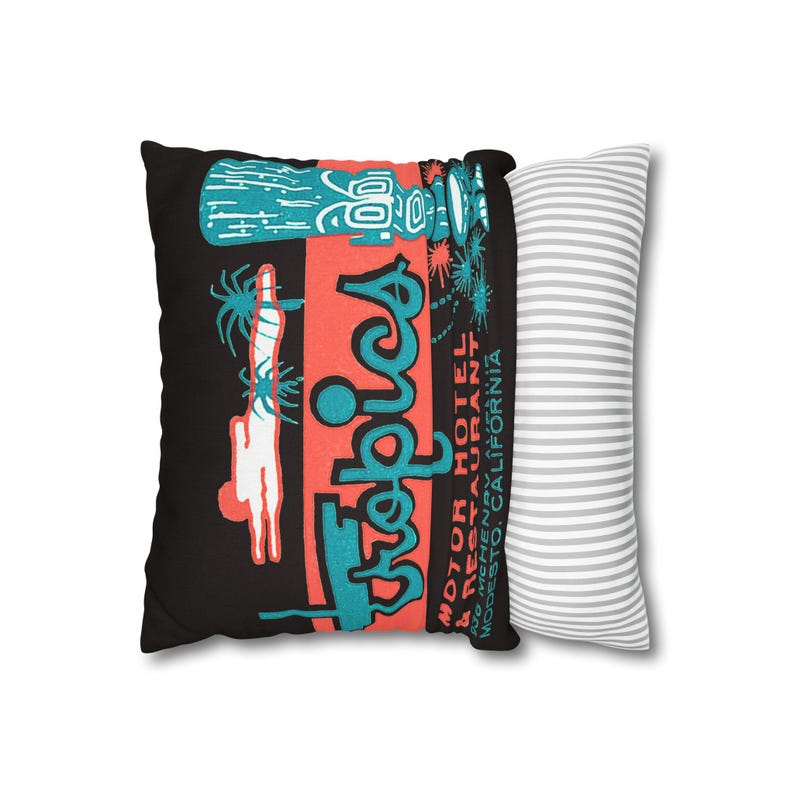 Peut inclure: Un coussin d&eacute;coratif avec un fond noir pr&eacute;sentant un design r&eacute;tro. Le design comprend le mot "Tropics" en turquoise, un rectangle rouge et un motif tiki turquoise. Le coussin est associ&eacute; &agrave; un coussin &agrave; rayures grises et blanches.