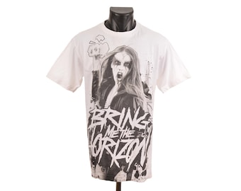 May include: White t-shirt featuring a black and white graphic of a person with long hair and dark makeup, screaming. The text "BRING ME THE HORIZON" is printed below the graphic in a distressed font. The shirt is displayed on a black mannequin.