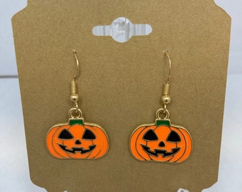 Op de afbeelding: Een paar gouden pompoen oorbellen met oranje en groen emaille. De oorbellen zijn op een bruine kaart met de tekst "Optie 1".