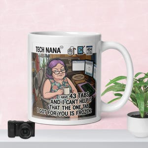 May include: A white ceramic mug featuring a cartoon illustration of a person with purple hair wearing headphones, sitting at a desk with computers. The text reads: TECH NANA, 404 ATTITUDE NOT FOUND, I HAVE 43 TABS AND I CAN'T HELP IT THAT THE ONE TAB I GOT FOR YOU IS FROZEN.