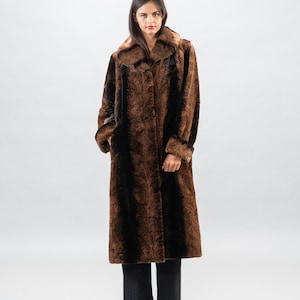 May include: A long brown and black fur coat with a collar. The coat is buttoned up the front and has a straight silhouette.