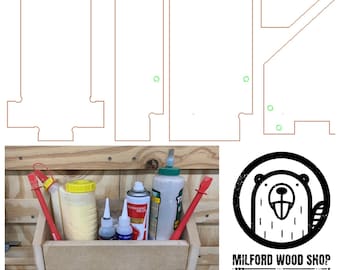 May include: A wooden wall shelf with a cutout design for holding bottles of glue and other craft supplies. The shelf is labeled "Milford Wood Shop - Maker".