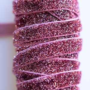 May include: Pink velvet ribbon with a sparkly finish. The ribbon is rolled up on a cardboard tube.