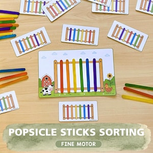 May include: A set of educational sorting cards featuring illustrations of farm fences with rainbow-colored popsicle sticks. The cards display a barn, a cow, a sunflower, and a chicken, designed for matching activities with colorful wooden sticks.