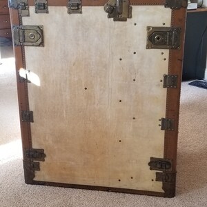 May include: A vintage brown leather suitcase with brass hardware and a white canvas interior. The suitcase has multiple clasps and buckles.