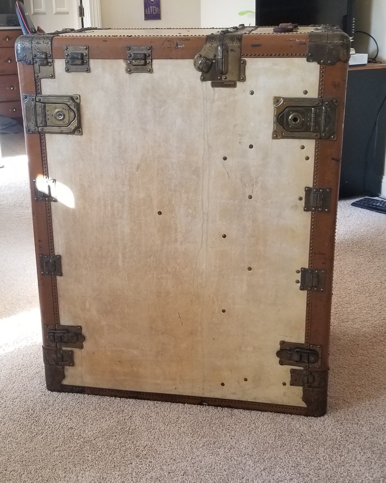 May include: A vintage brown leather suitcase with brass hardware and a white canvas interior. The suitcase has multiple clasps and buckles.