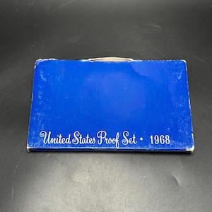 May include: A blue box with the text "United States Proof Set • 1968" in white script. The box is rectangular and appears to be made of cardboard. The box has some wear and tear.