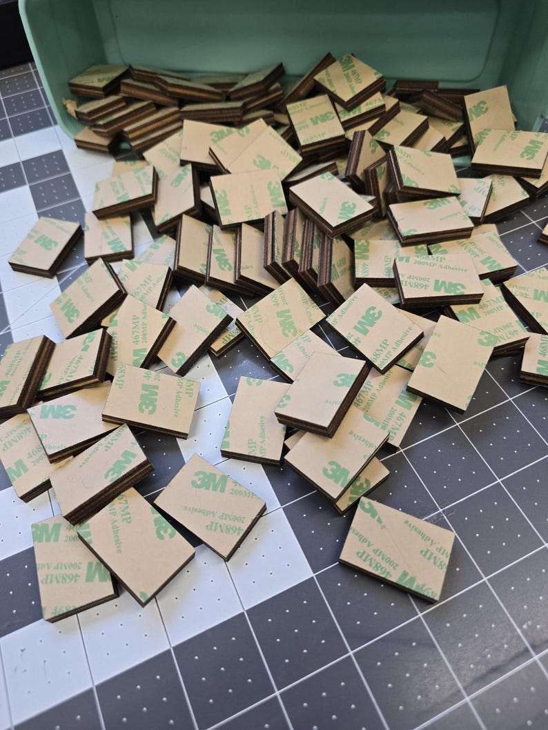 May include: A large pile of brown and green adhesive squares with the 3M logo printed on them.