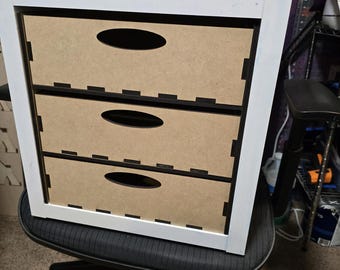 Op de afbeelding: Witte organizer met drie laden met zwarte afwerking en bruine laden. De organizer staat op een zwarte bureaustoel met wielen.