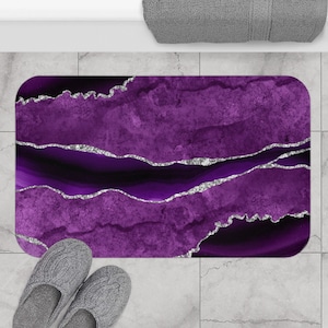 May include: Purple and silver bath mat with an agate design. The mat has a textured surface and is made of a soft, absorbent material.