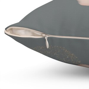 a close-up view of a gray pillow with a zipper and a gold glitter design on the right side.