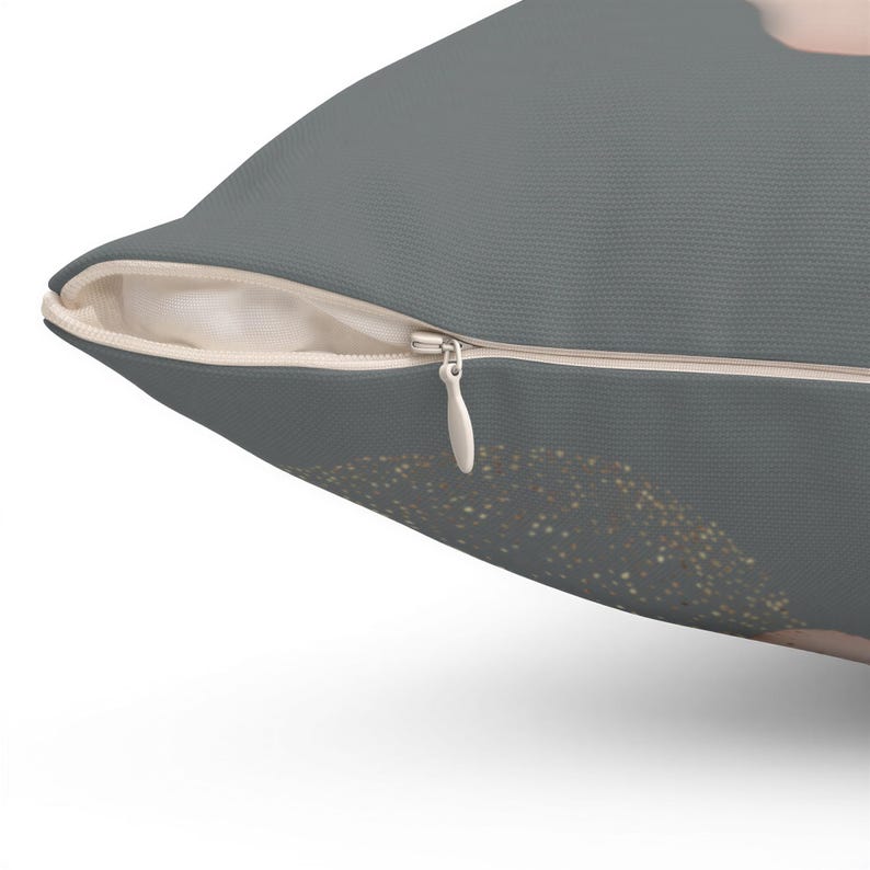 a close-up view of a gray pillow with a zipper and a gold glitter design on the right side.