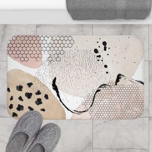 May include: Abstract bath mat with pink, brown, and black geometric shapes and patterns on a white background.