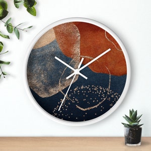 May include: A white round clock with a blue, orange, and gold abstract design. The clock hands are white.