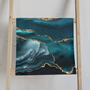 May include: Abstract teal and blue agate print with gold glitter accents. The print features a swirling pattern of teal and blue colours with gold glitter accents along the edges.