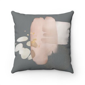 The image is a square pillow with a gray background and abstract art featuring pink and white brushstrokes.