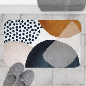May include: Abstract bath mat with a white background and colorful shapes in shades of blue, brown, and pink. The shapes are abstract and resemble watercolors.