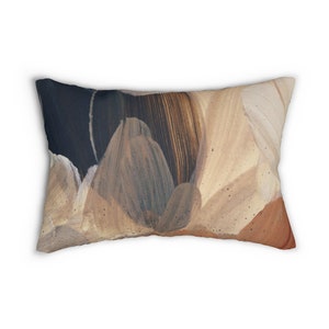 May include: Rectangular decorative pillow with an abstract design. The pillow features a blend of colors, including dark blue, beige, and brown, creating a textured, artistic appearance. The design resembles brushstrokes or layered petals.