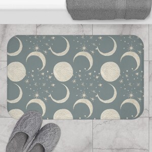 Può includere: Un tappetino da bagno blu con un motivo a mezzaluna e stelle bianche.