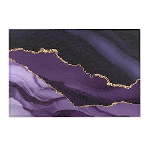 May include: Rectangular decorative mat with a dark purple and black abstract design. The design features flowing, layered shapes with gold glitter accents. The mat has a textured appearance, suitable for home decor.