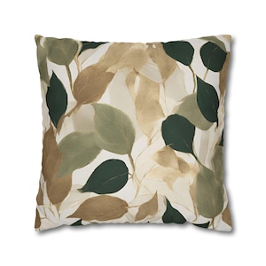 May include: A square throw pillow with a white background and a pattern of green and brown leaves.