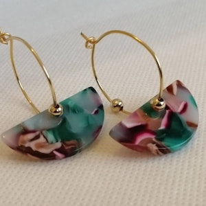 Op de afbeelding: Een paar gouden oorringen met een halfrond, gemarmerd ontwerp. De oorbellen hebben een mix van kleuren, waaronder groen, roze, bruin en wit. De ringen zijn gemaakt van goudkleurig metaal en hebben een kleine gouden kraal aan de basis van de halve cirkel.