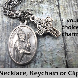 May include: Silver necklace with a St. Patrick medal and a Celtic cross charm. The necklace is available as a keychain or clip.