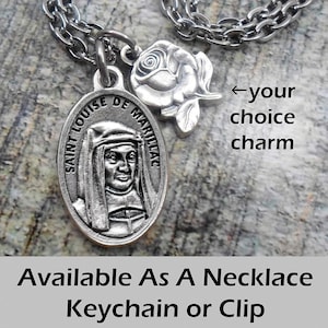 May include: A silver-toned necklace with a Saint Louise de Marillac pendant and a rose charm. The oval pendant features an image of Saint Louise. The text "Available As A Necklace Keychain or Clip" is at the bottom.