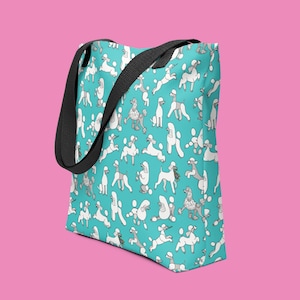 May include: A turquoise tote bag with a white poodle pattern. The bag has black straps.