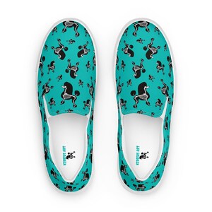 Könnte beinhalten: Ein Paar weiße Canvas-Slipper mit türkisfarbenem Hintergrund und einem schwarzen und weißen Skelett-Pudel-Druck. Die Schuhe haben den Text "KERRIUS ART" auf der Innenseite.