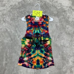 May include: A tie-dye tank top with a black and white graphic of a goat wearing a bandana. The tank top is a mix of blue, green, orange, yellow, and red colors.