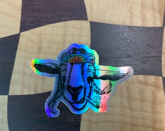 May include: A holographic sticker of a goat wearing a hat with the text "BMFS" on it. The goat is smoking a joint.