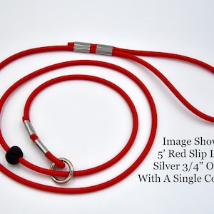 May include: A red slip lead for dogs, featuring a silver O-ring and cord lock. The lead is approximately 5 feet long.