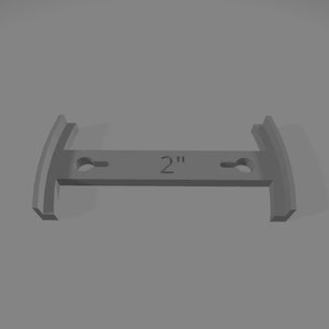 Puede incluir: Un soporte de metal gris con dos agujeros y el texto "2" impreso en él. El soporte tiene 5 cm de largo y tiene una forma curva en cada extremo.