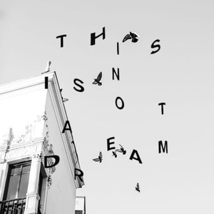May include: Black and white photograph of a building with the words "THIS IS NOT A DREAM" spelled out in the sky using birds.