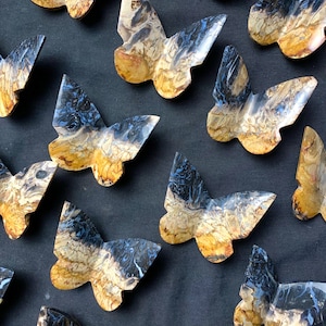May include: A collection of wooden butterfly wall decor with a blue and gold marbled pattern. The butterflies are arranged in a random pattern on a dark blue background.