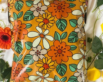 May include: A clear plastic mailing envelope with a retro floral pattern in shades of orange, yellow, green, and white. The envelope has a sealed flap and a white border.