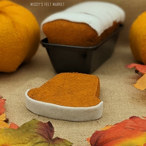 May include: A felt loaf of bread with white frosting in a black baking pan, next to a felt pumpkin and fall leaves.  The text "MISSY'S FELT MARKET" is visible in the image.
