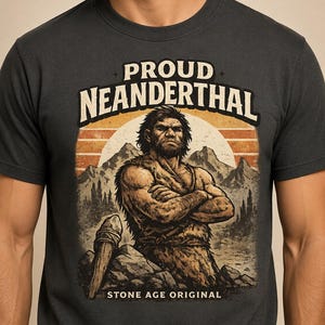 May include: Dark gray t-shirt featuring a graphic of a Neanderthal man with crossed arms, set against a mountain and sunset backdrop. The text reads "PROUD NEANDERTHAL" above the image and "STONE AGE ORIGINAL" below.