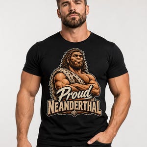 May include: A black short-sleeved t-shirt featuring a graphic of a muscular Neanderthal with long hair, wearing a fur-patterned wrap. The text "Proud NEANDERTHAL" is printed in a bold, stylised font across the lower portion of the graphic design.